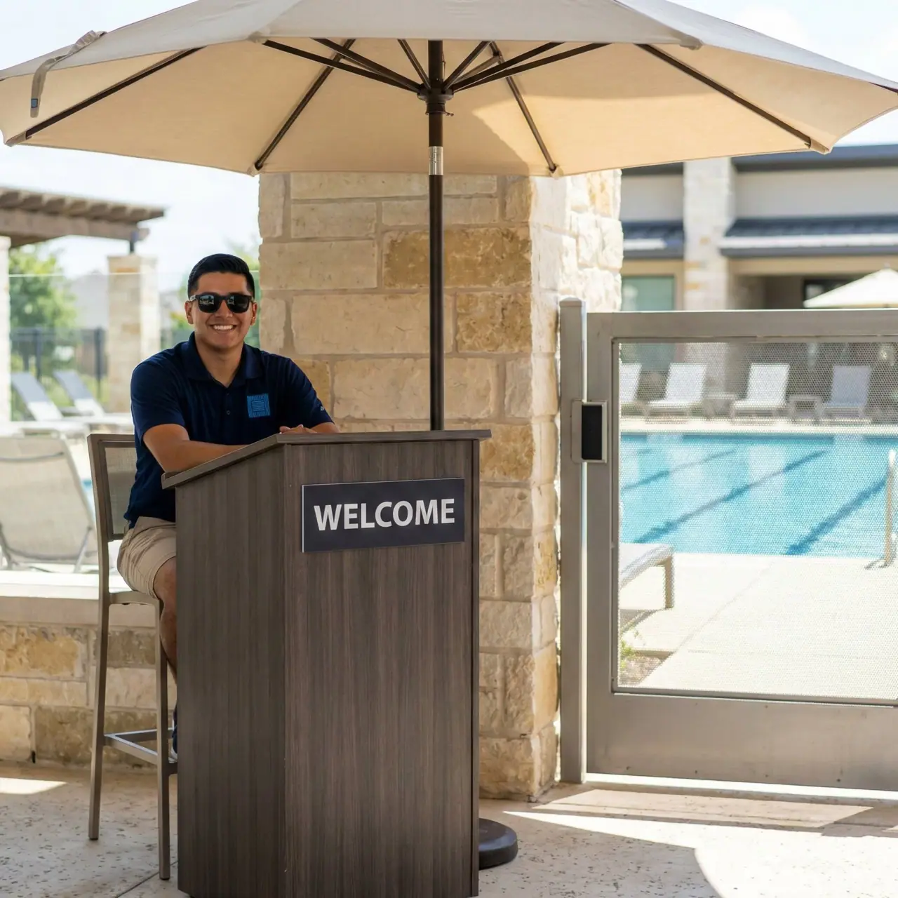 Pool attendant at a welcome podium beside the gate of a community pool